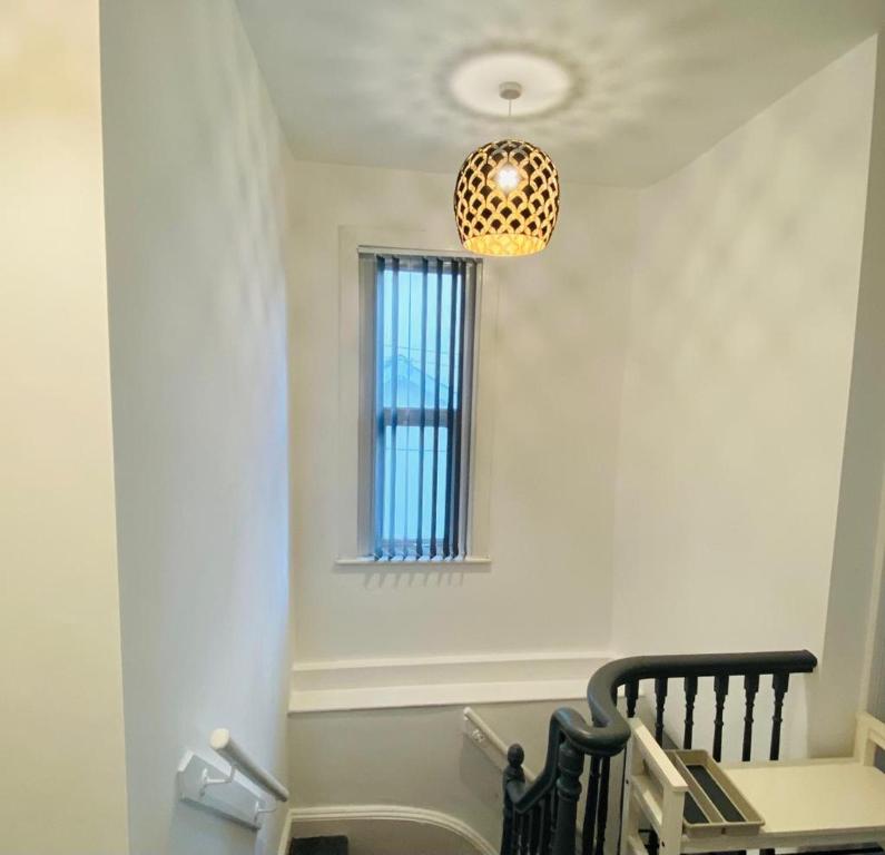 a room with a staircase with a window and a chandelier at Caerau Heights in Newport