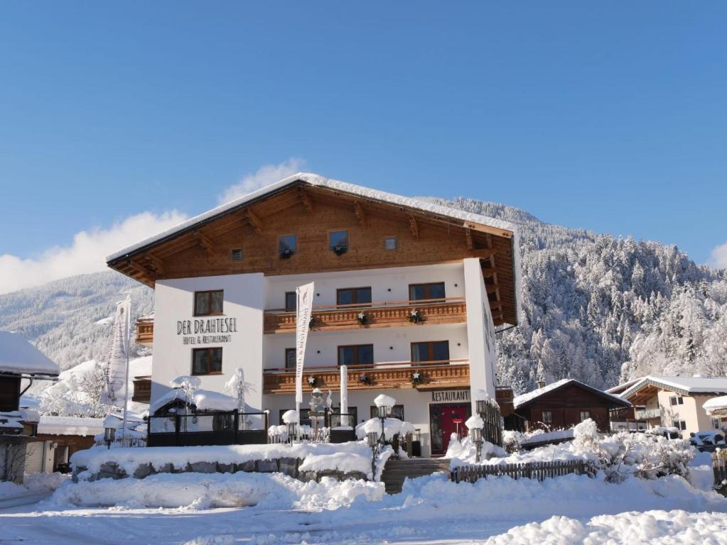 un gran edificio en la nieve con una montaña en Hotel Der Drahtesel, en Bramberg am Wildkogel