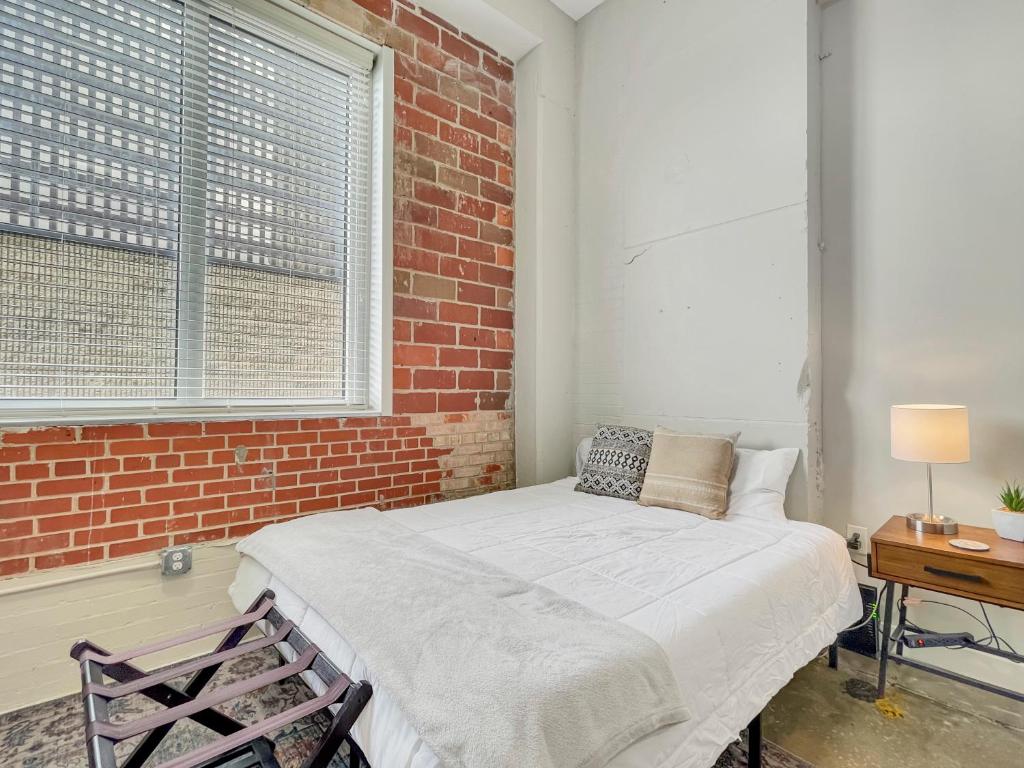a bed in a room with a brick wall at Stunning Downtown Studio With Rooftop Patio in Des Moines