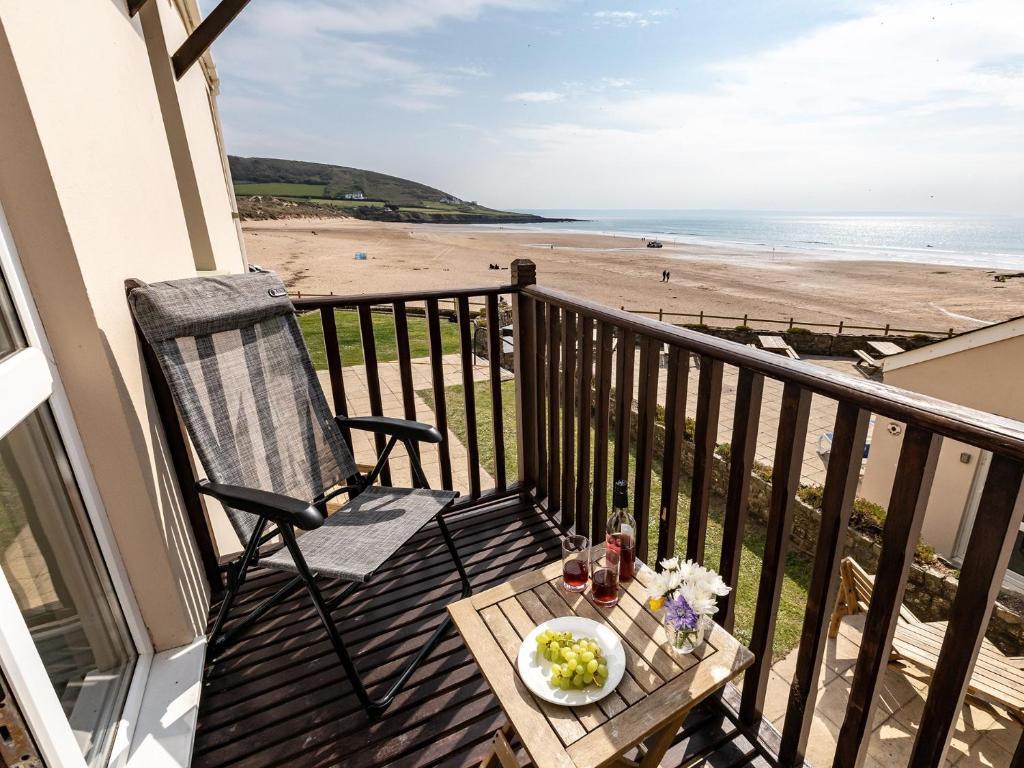 a balcony with a chair and a table and the beach at 2 Bed in Croyde 87110 in Croyde