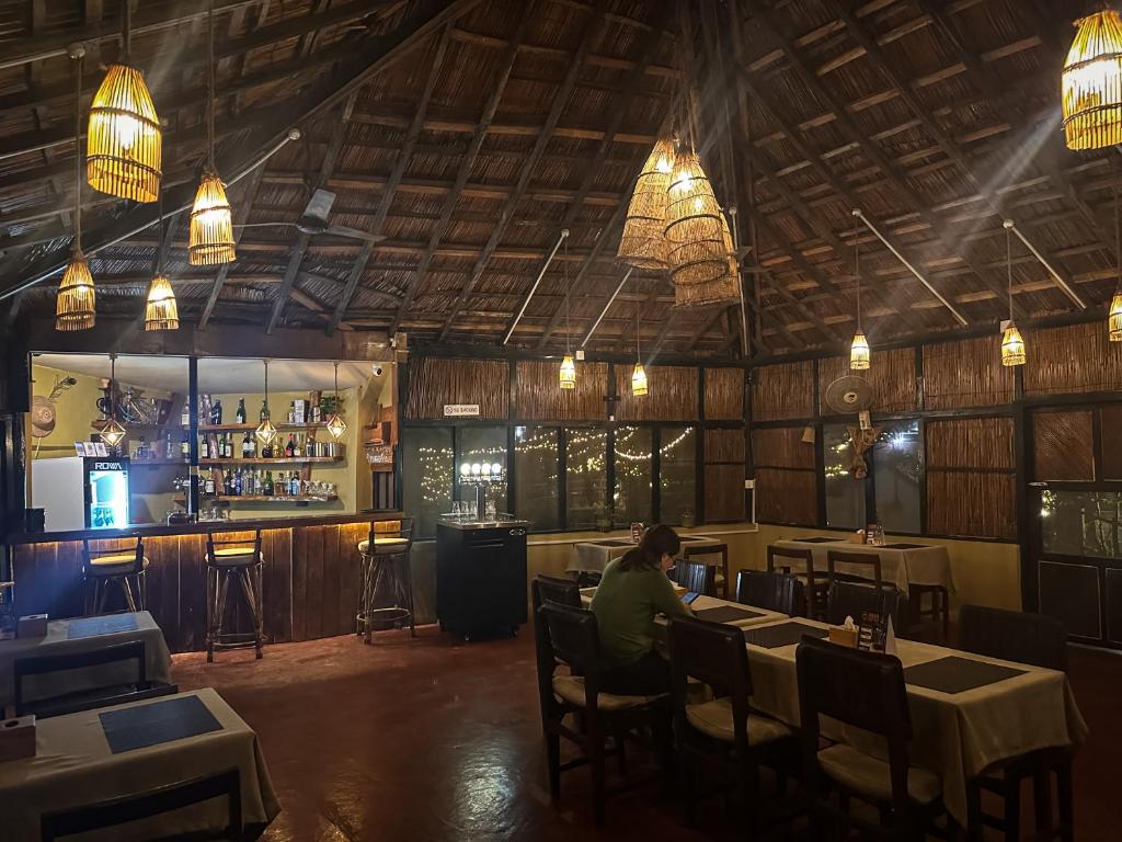 a man sitting at a table in a restaurant at Hotel Tharu Garden And Beer Bar in Chitwan