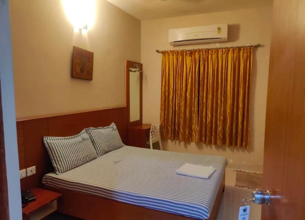 a small bedroom with a bed and a window at Skylink residency in Chennai