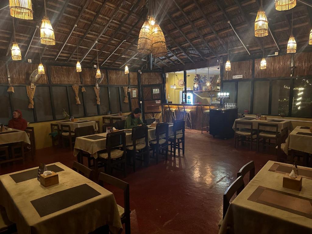 a dining room with tables and chairs and lights at Hotel Tharu Garden And Beer Bar in Chitwan