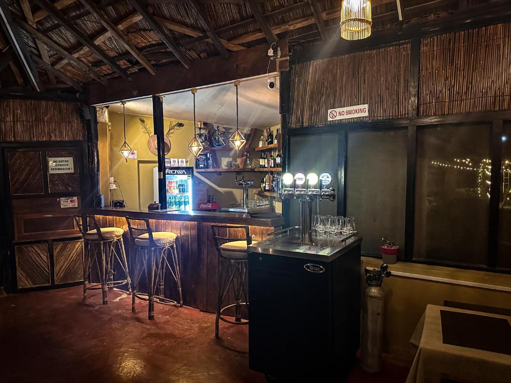 a bar with stools and a counter in a room at Hotel Tharu Garden And Beer Bar in Chitwan