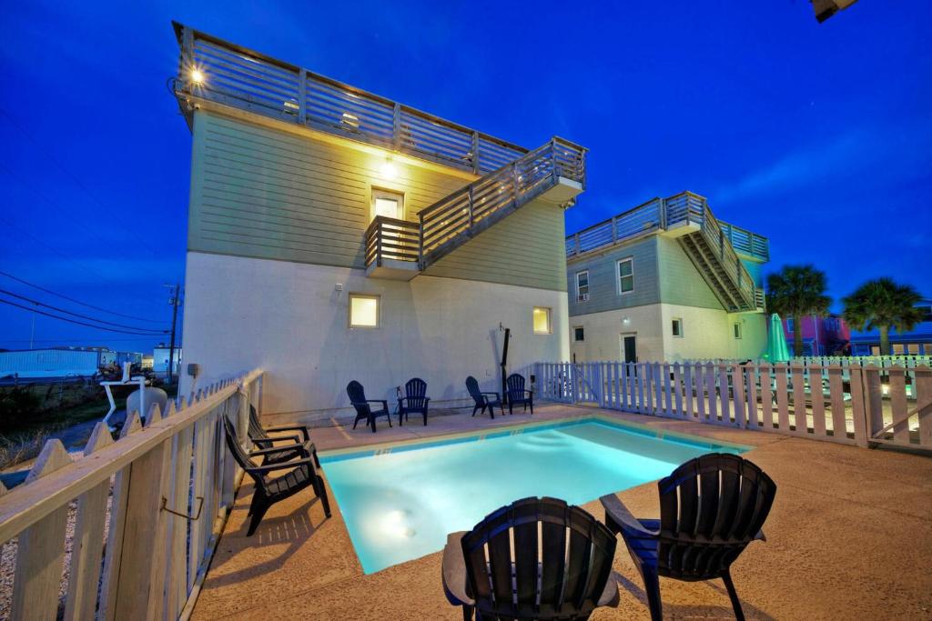 a swimming pool with chairs and a house at Stella Maris Golf Cart Zone Near Beach Rooftop in Port Aransas