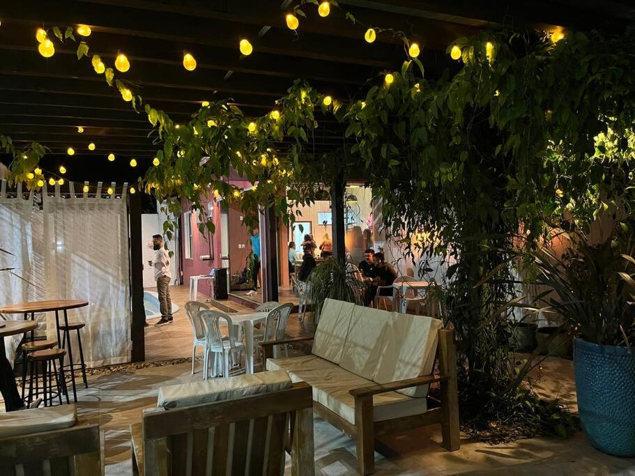 un patio con banco de madera, mesas y luces en Casa e espaço para festas - Espaço Maréas, en São Francisco do Sul