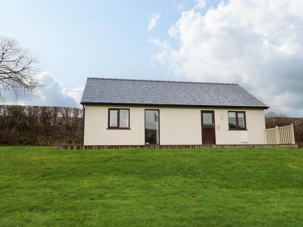 a small white house on a grassy field at Country Cottage in Brecon