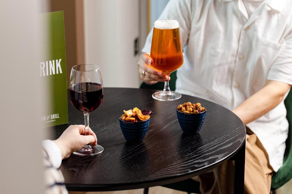 two people sitting at a table with two glasses of wine and snacks at Leonardo Inn Aberdeen Airport in Dyce