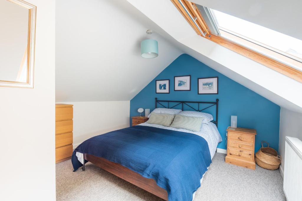 a bedroom with a blue bed in a attic at Riverside Bothy In Heart of Scenic Harbour Village in Solva