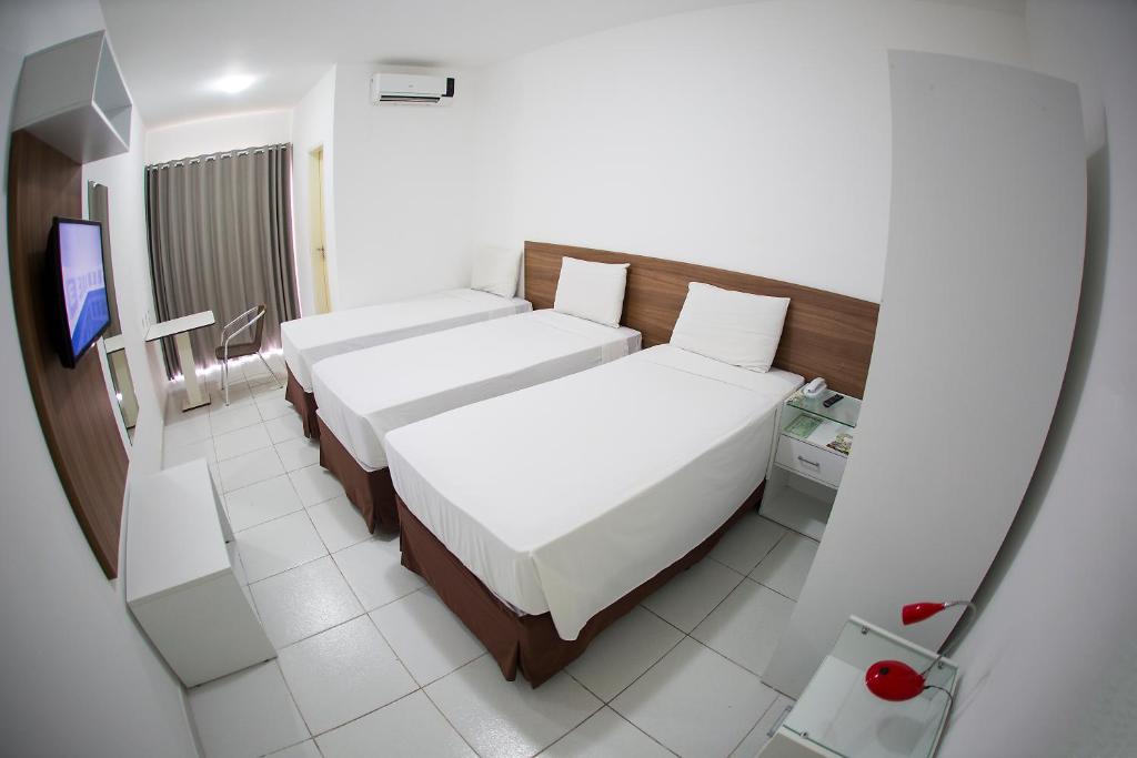 Araras Praia Hotel في أراكاجو: غرفه فندقيه سريرين وتلفزيون