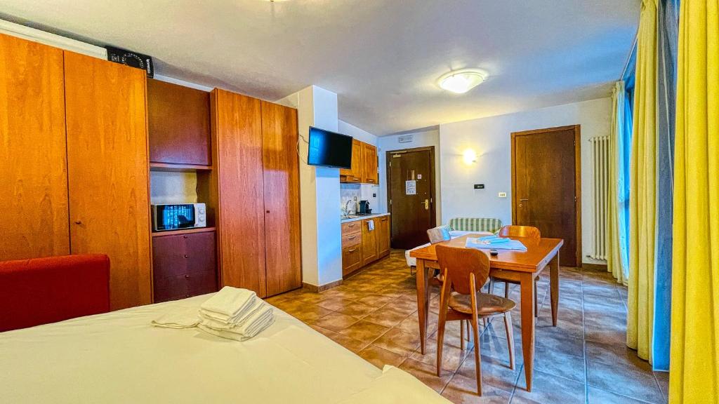 a room with a dining table and a kitchen at Appartamento Smith Moscato - Affitti Brevi Italia in Bardonecchia