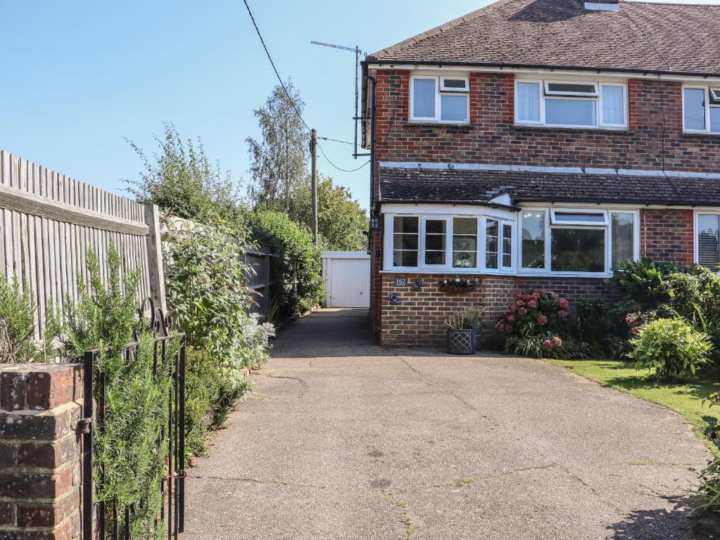 a brick house with a fence and a driveway at Lavender Cottage in Hailsham