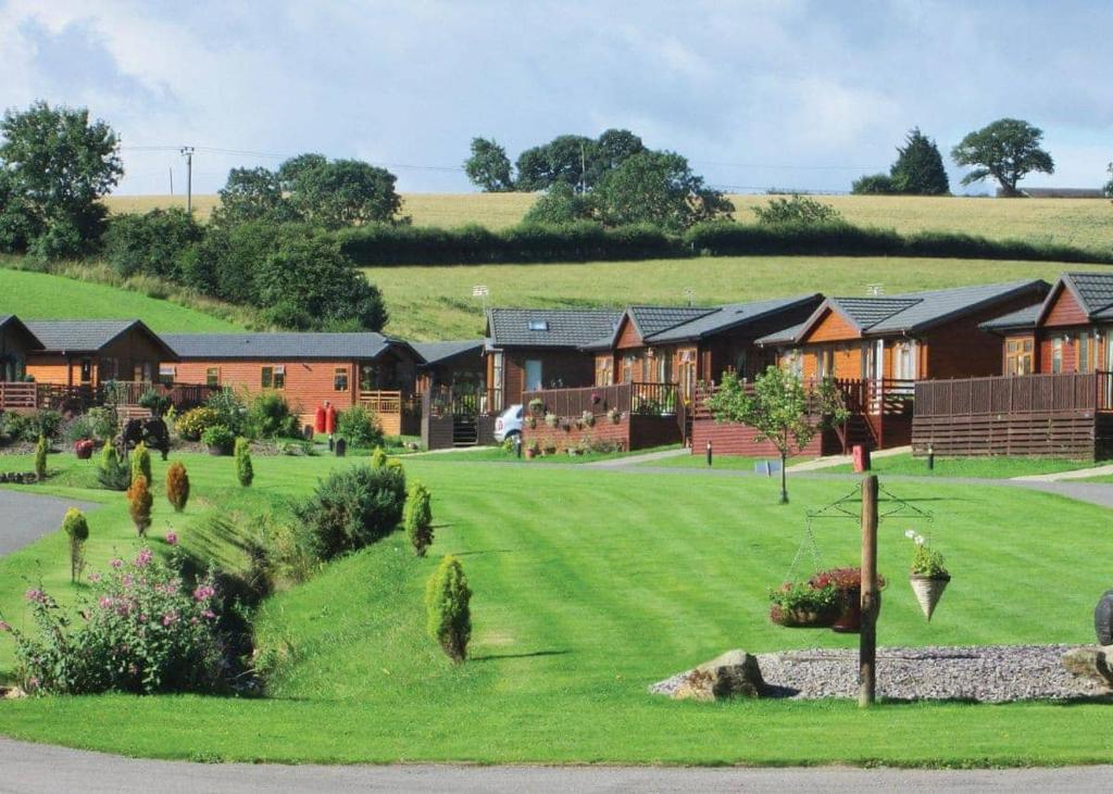 a row of houses on a hill with a green yard at Badgers Retreat Holiday Park in Hunton