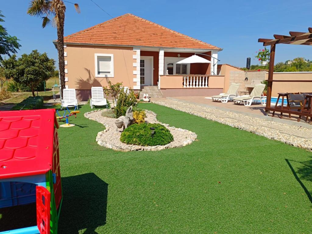 ein Haus mit einem Garten mit Rasen und Spielplatz in der Unterkunft Holiday Home Merie with pool in Benkovac