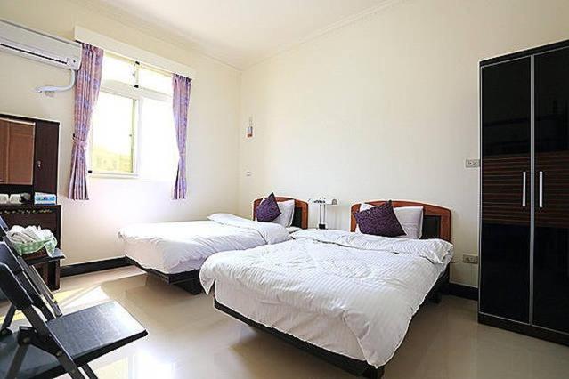 a bedroom with two beds and a desk and a window at 成功民宿 KM Bed and Breakfast in Jinhu