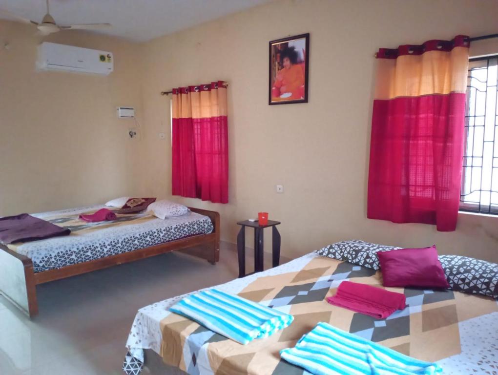2 camas en una habitación con cortinas rojas en Ahobila Delux Homes, en Tiruchchirāppalli