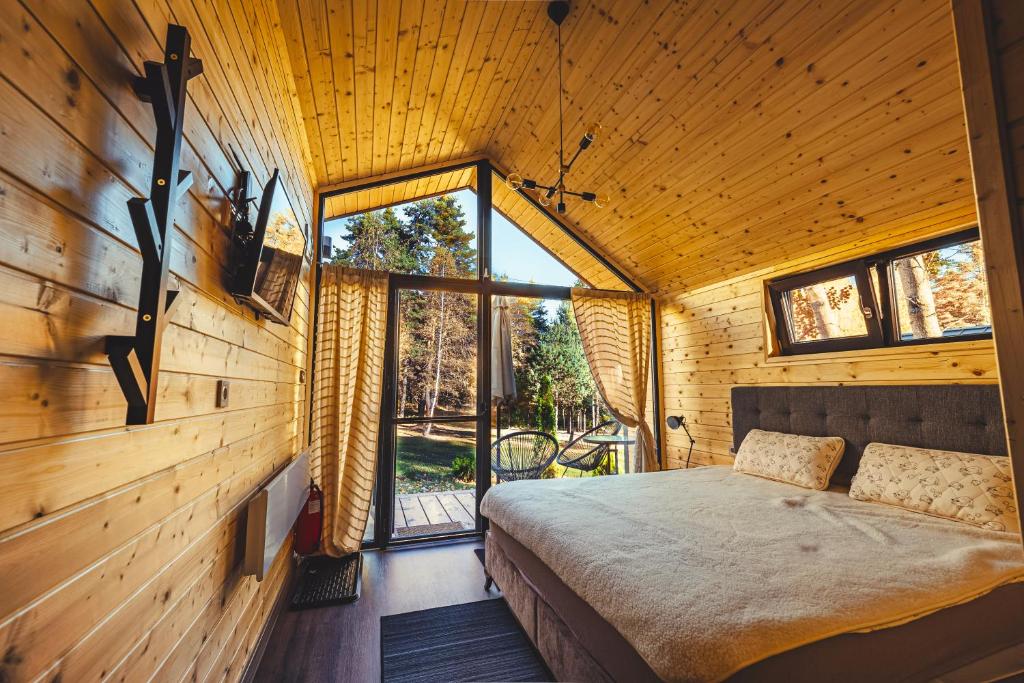 um quarto num chalé de madeira com uma cama e uma janela em Saint Constantine Mountain Retreat em Peshtera