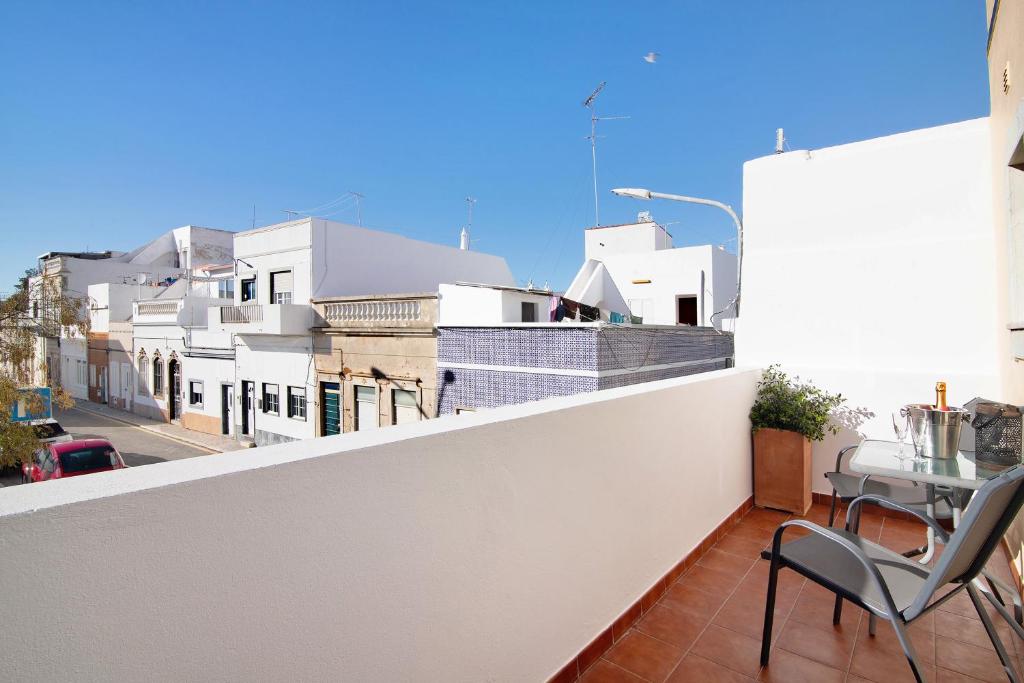 a balcony with chairs and a view of a city at Casa Mar-a-vila in Olhão