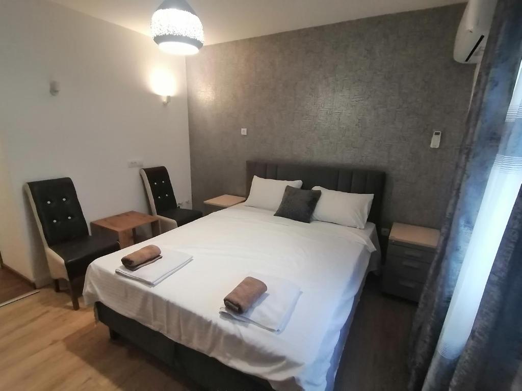 a bedroom with a large white bed and two chairs at Apartmani Mia in Kraljevo