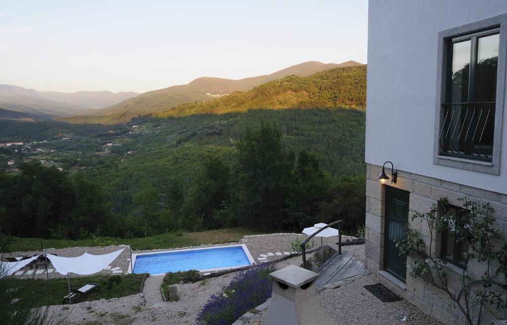 a house with a swimming pool and mountains in the background at Quinta da Madrugada in Avô