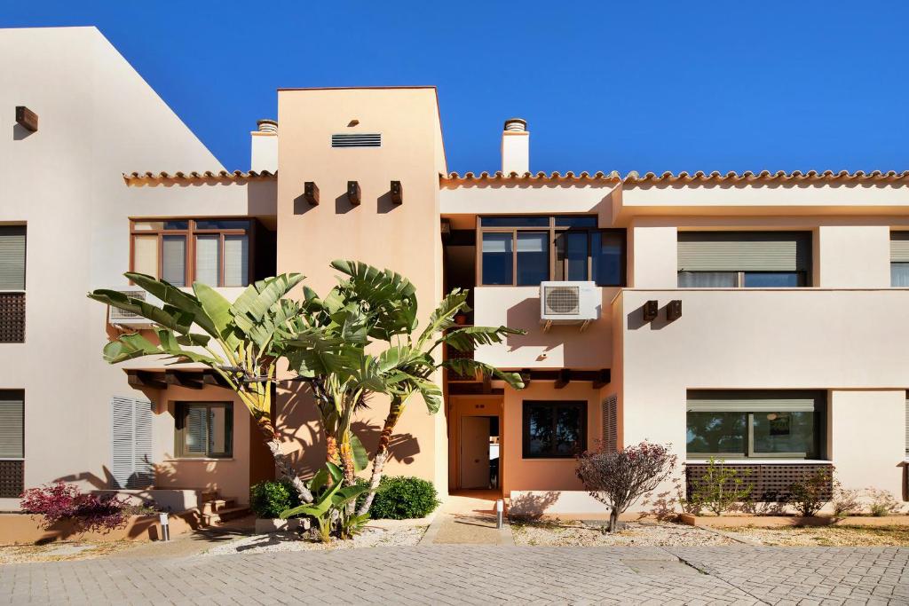 a house in the desert with a palm tree in front at Apartamento Villanueva Golf in Puerto Real