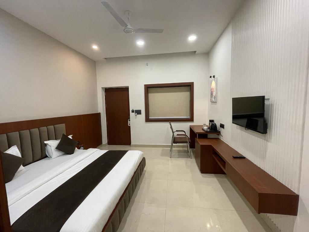 a bedroom with a large bed and a flat screen tv at The Kedar Resort in Mathura