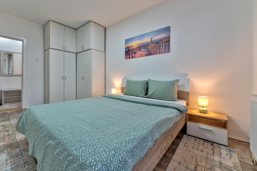 Schlafzimmer mit einem großen Bett mit blauer Tagesdecke in der Unterkunft White House NS in Novi Sad