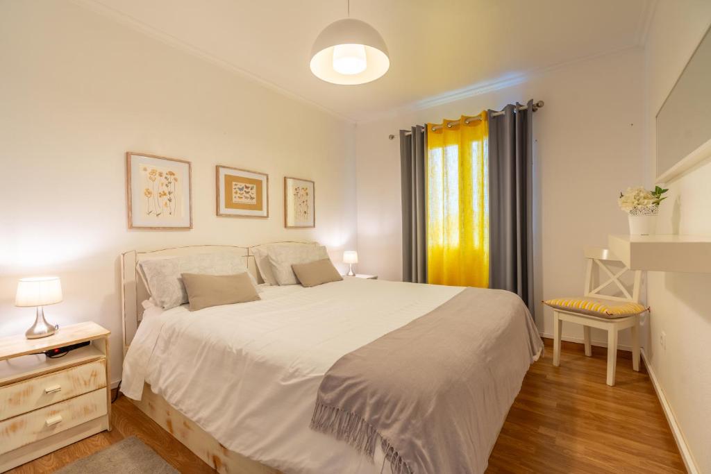 sypialnia z dużym białym łóżkiem i oknem w obiekcie Campo & Mar Apartments w mieście Porto Moniz