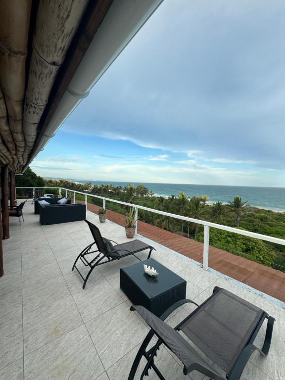 a patio with chairs and a table and the ocean at Peri-Peri Divers B&B Morrungulo in Cabo Nhabacal