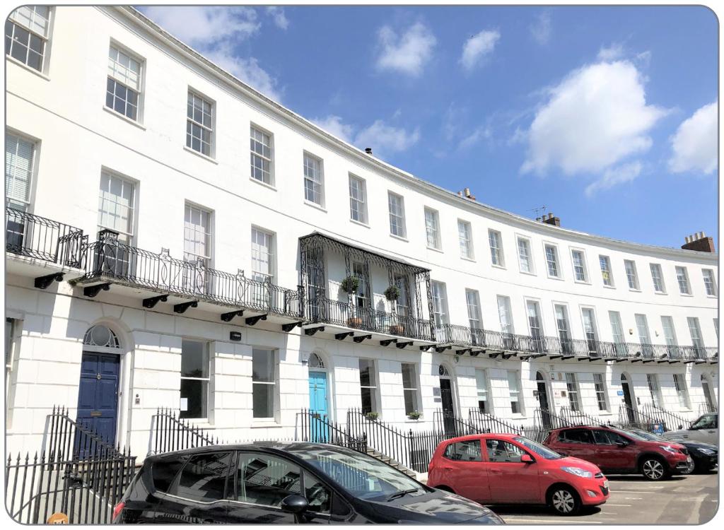 un edificio blanco con coches estacionados frente a él en The Dulwich en Cheltenham