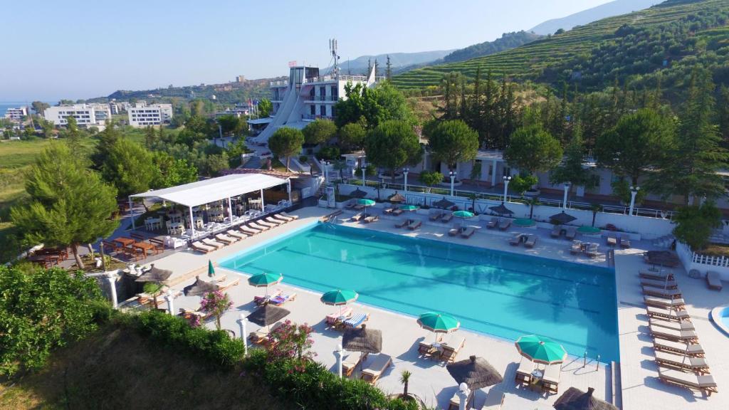 a pool at a hotel with chairs and umbrellas at Edva Resort in Vlorë