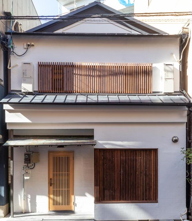 a white house with wooden doors and a balcony at 静響の宿 Silent Echo Inn in Osaka
