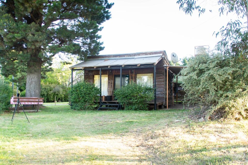 a log cabin in a yard with a tree at Cabañas El Viejo Sauce in Tandil
