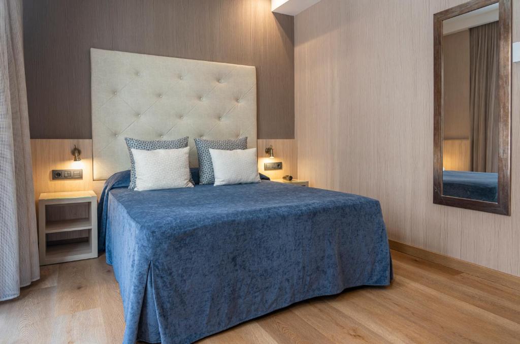 a bedroom with a large bed with a blue blanket at Hotel Rialto in Barcelona