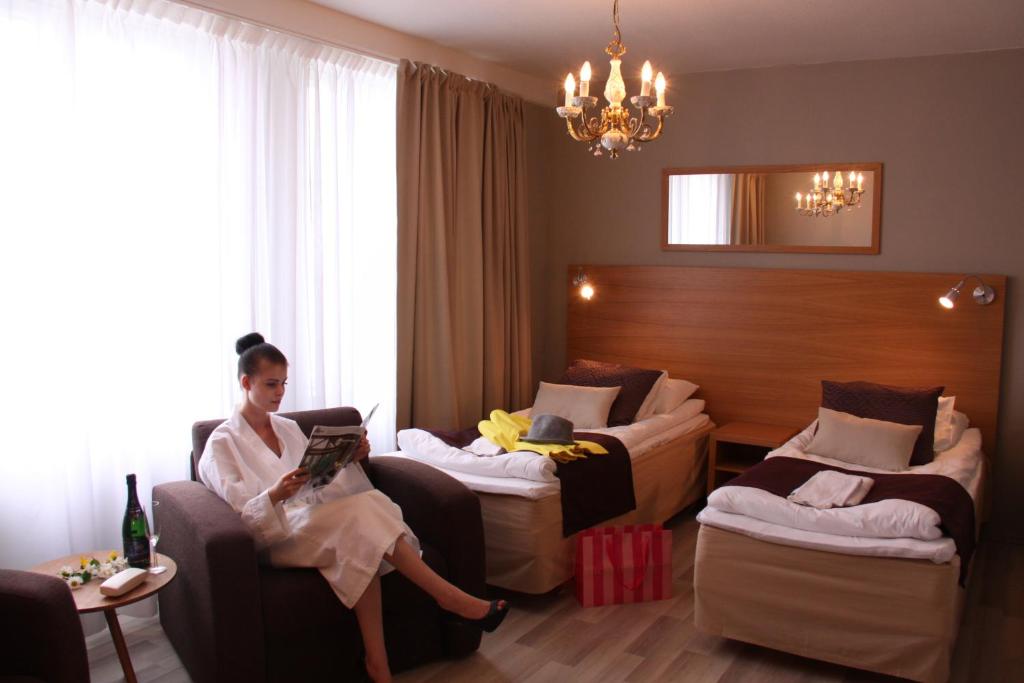 uma mulher sentada num sofá num quarto de hotel em Loimaan Seurahuone em Loimaa