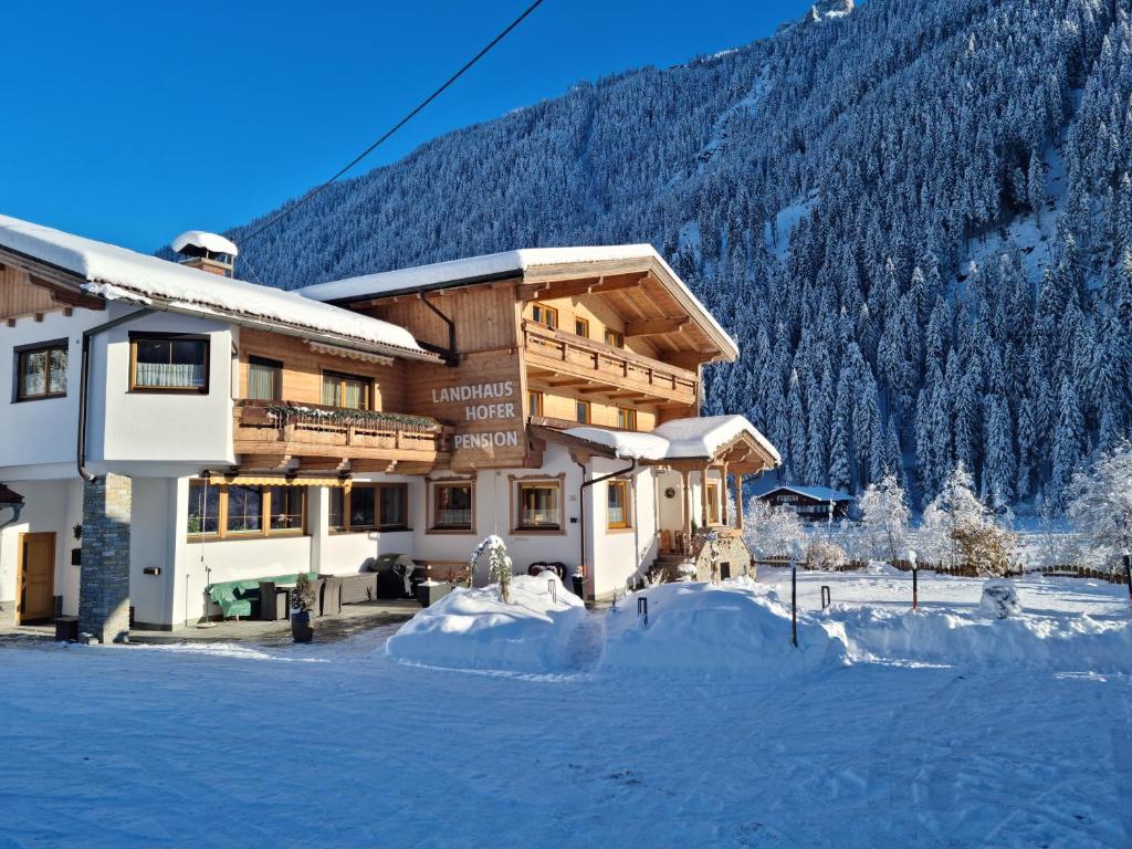 a large building with snow in front of a mountain at Landhaus Hofer in Neustift im Stubaital