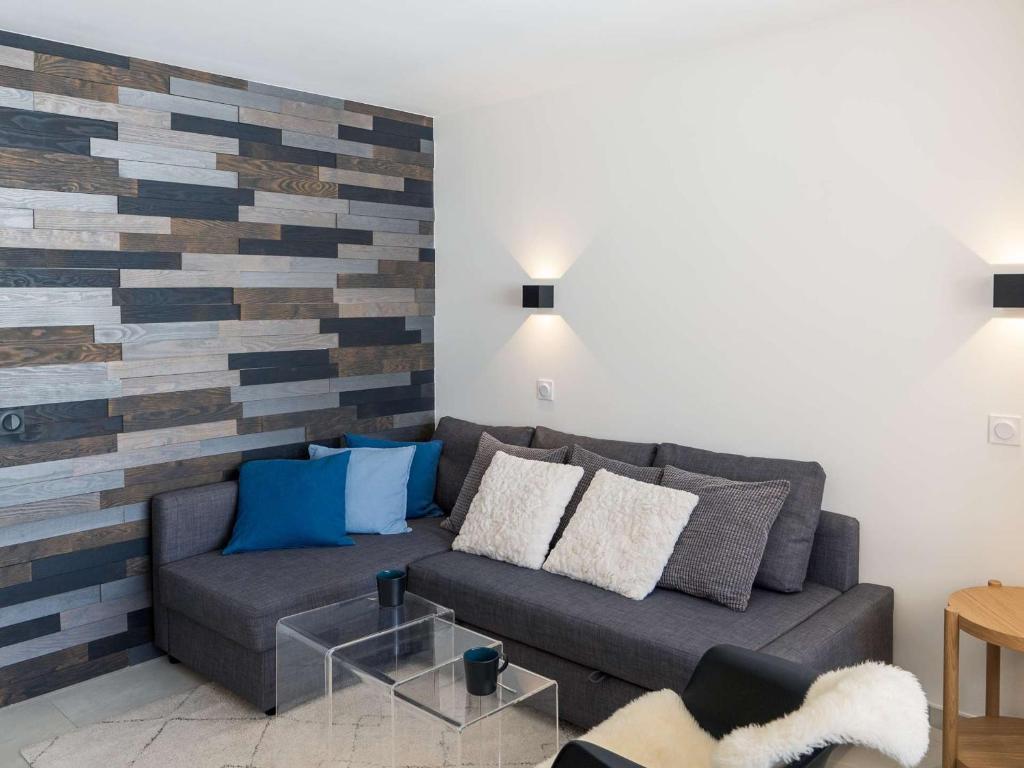 a living room with a couch and a wooden accent wall at Appartement Val Thorens, 2 pièces, 4 personnes - FR-1-637-66 in Val Thorens