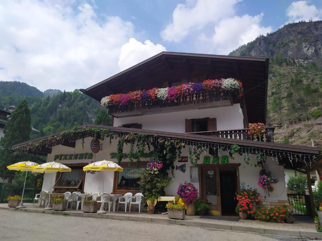 a building with flowers and umbrellas in front of it at Pizzeria Marmolada Camere in Sottoguda