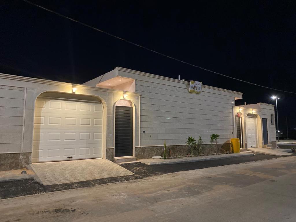 une maison blanche avec garage la nuit dans l'établissement شاليه ألو, à Al Bukayriyah
