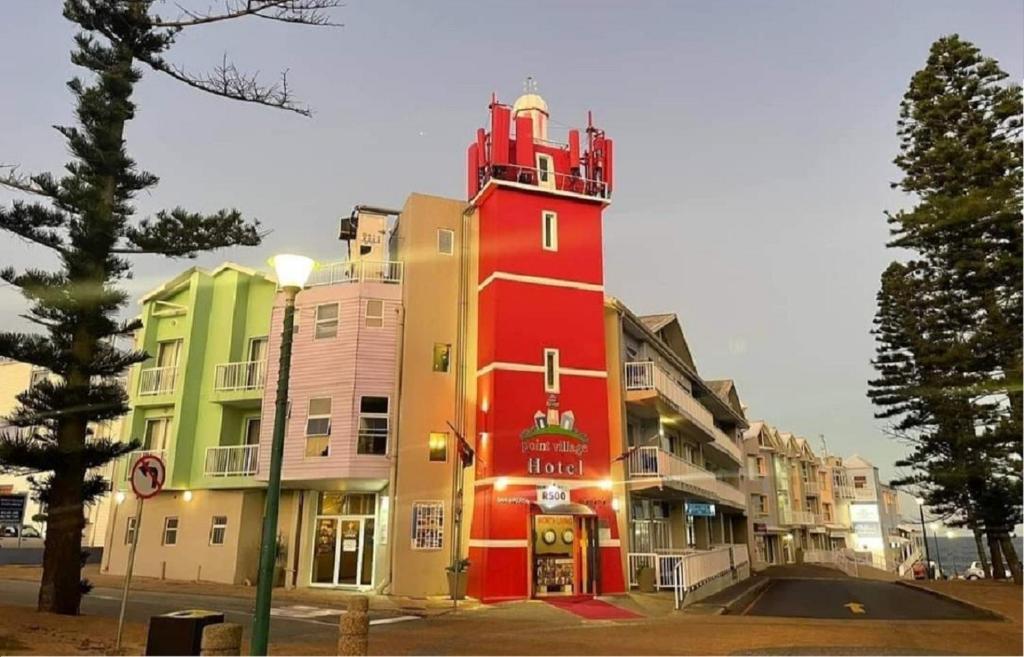a red building with a tower on a street at Point Village Hotel and Self Catering in Mossel Bay