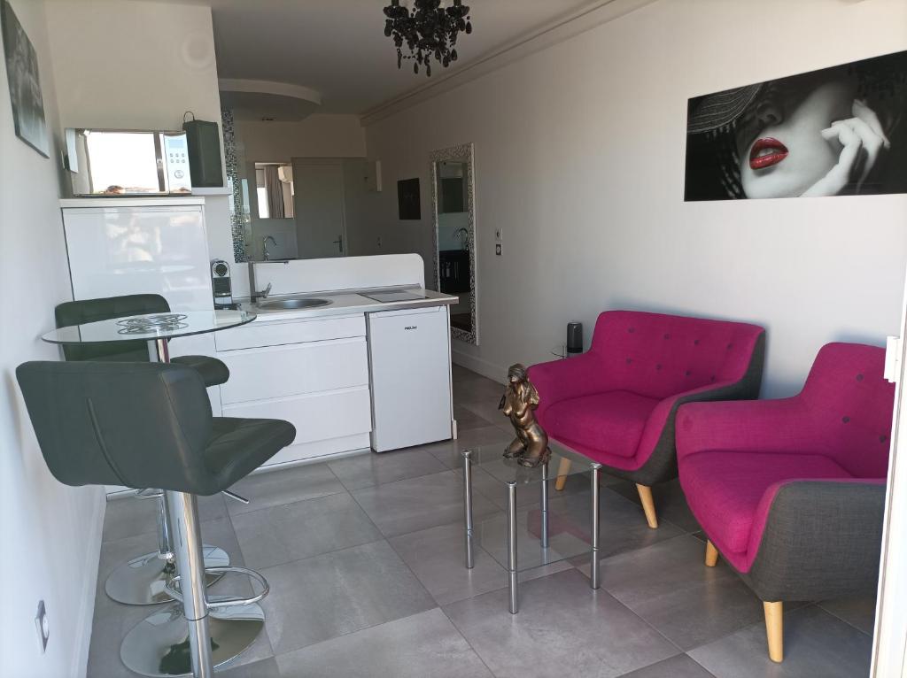 een keuken met roze stoelen en een tafel in een kamer bij Village Naturiste Studio Luxe in Cap d'Agde
