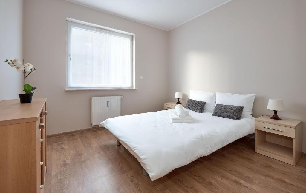 um quarto branco com uma grande cama branca e uma janela em Osiedle Zwycięstwa Standard Apartment em Poznań