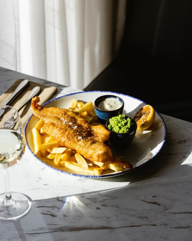 a plate of food with fish and fries on a table at Leonardo Hotel Manchester Central in Manchester