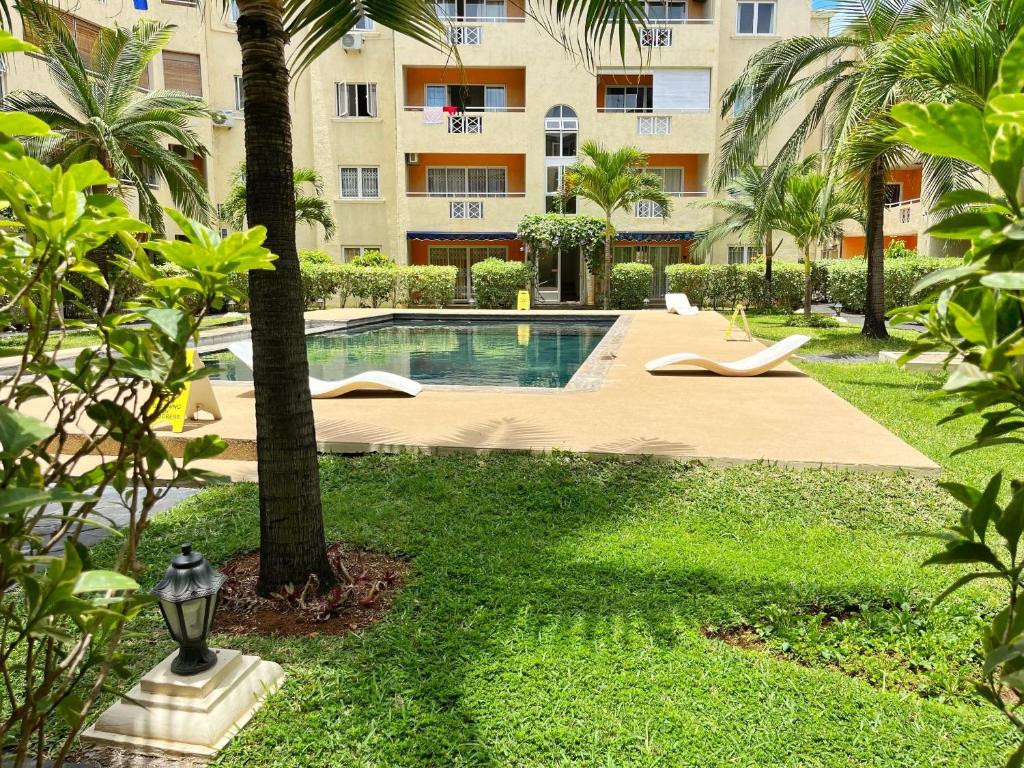 a swimming pool in front of a building with palm trees at C9 Tamarinier in Flic-en-Flac
