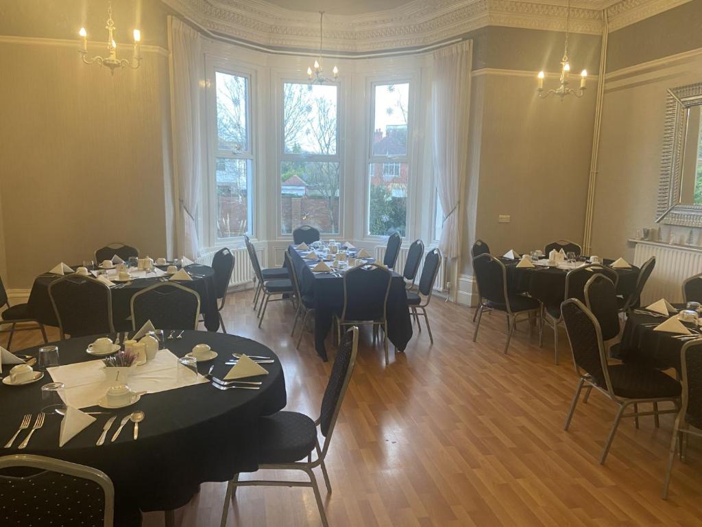 a dining room with tables and chairs and windows at Salfordian in Southport