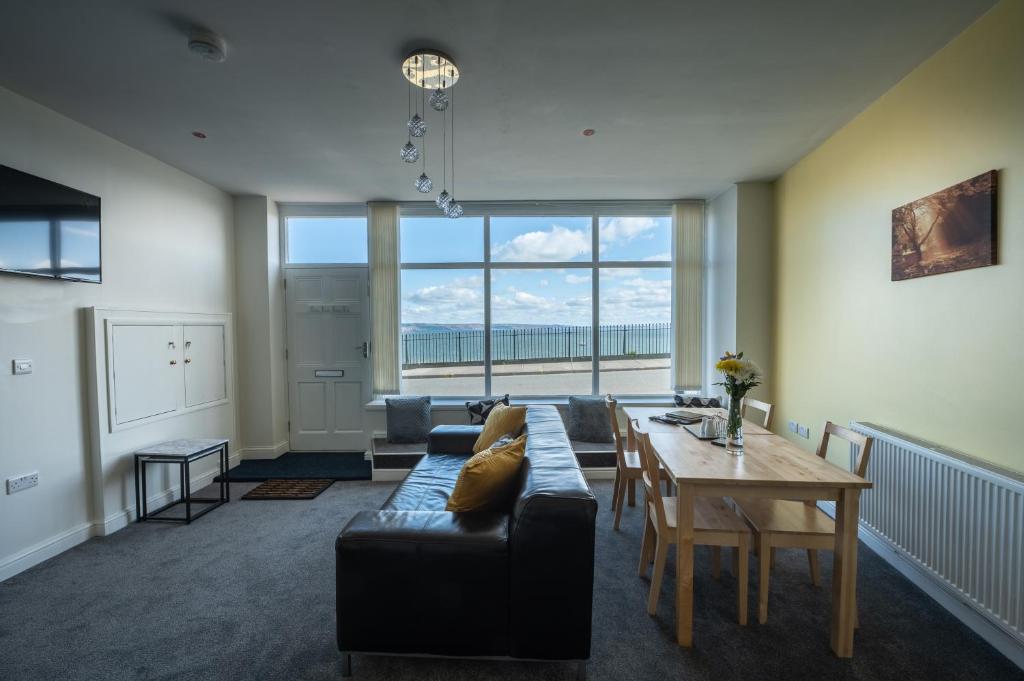 a living room with a couch and a table at Central Tenby North Beach Apartment with Parking in Pembrokeshire