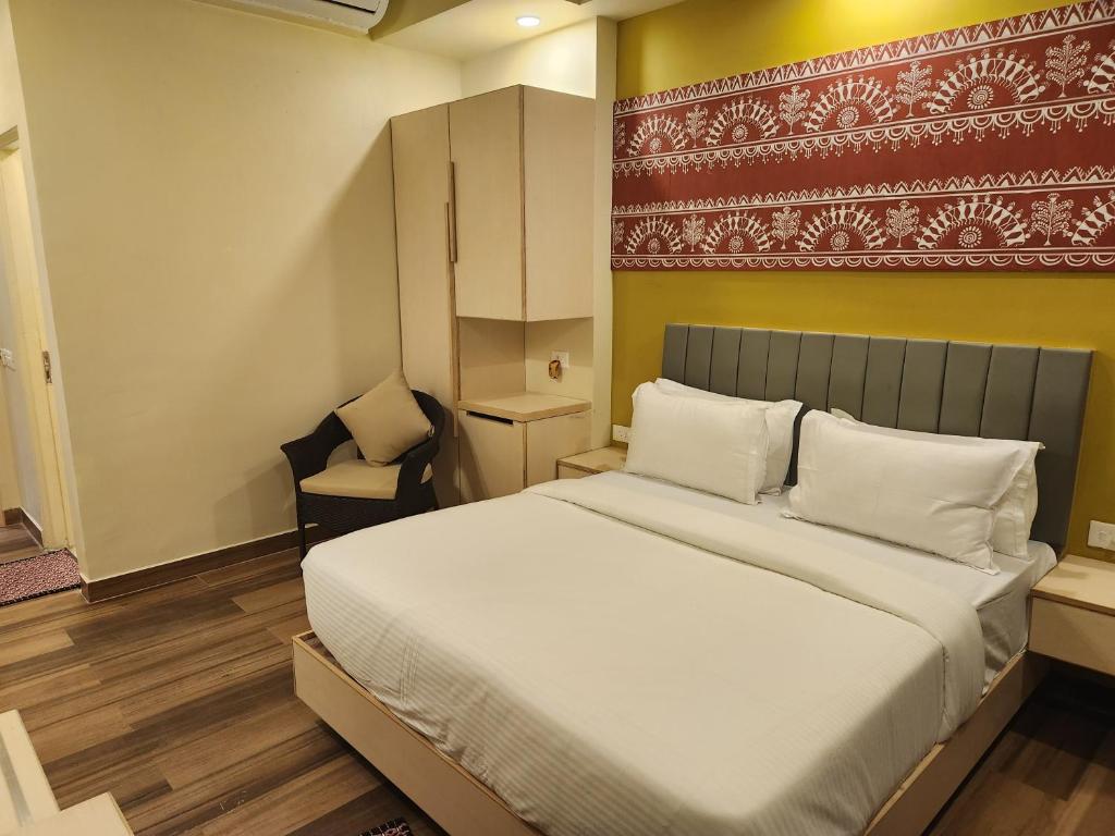 a bedroom with a large white bed and a chair at SHAMUKA HOTEL in Puri