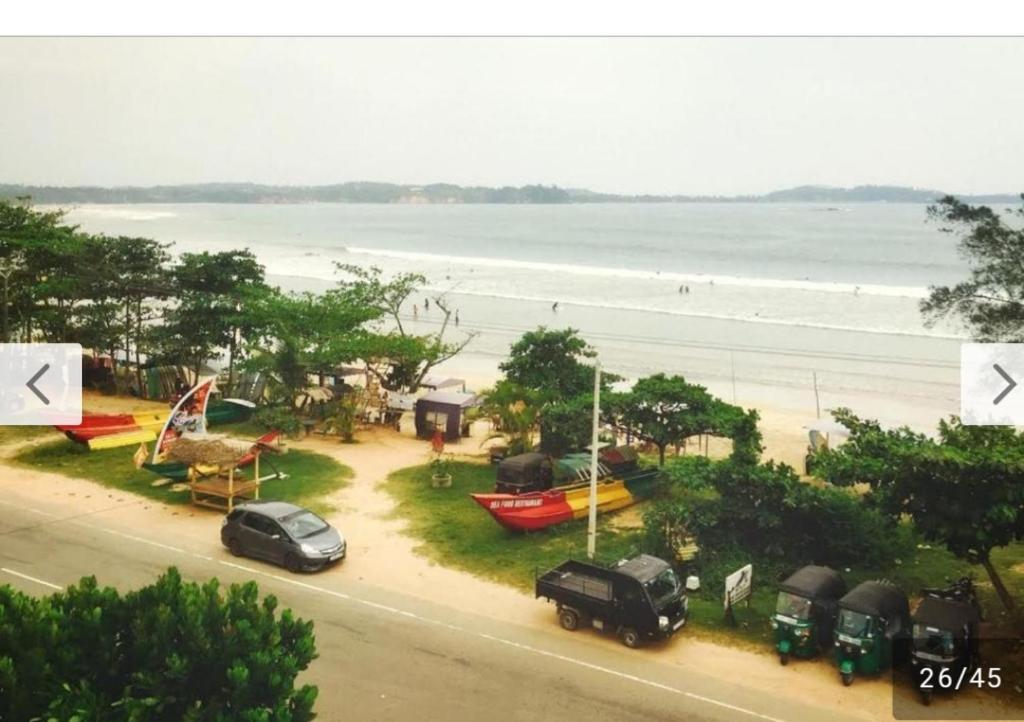 a view of a beach with cars parked on a street at Raymond Place -REDSTAR in Weligama