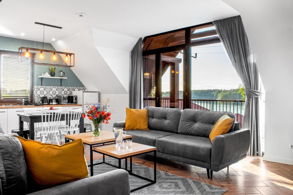 a living room with a couch and a kitchen at Apartamenty Pod Kominkiem in Rydzewo