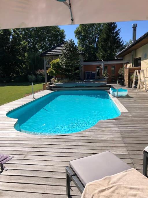 une grande piscine bleue sur une terrasse en bois dans l'établissement Le Clos des Eaux, à Tailly